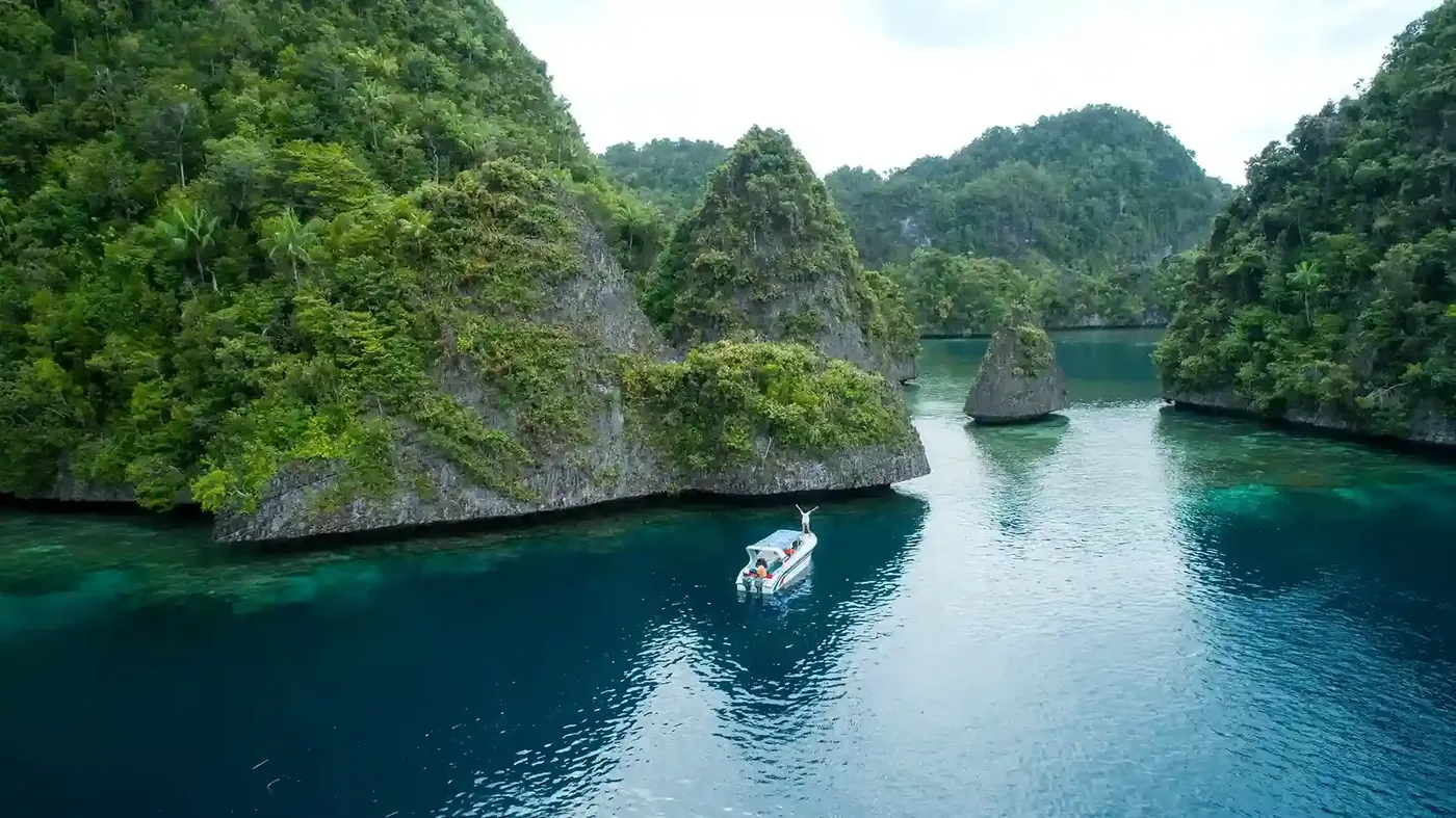 A tender running the narrow channel between two towering jungle-topped limestone walls
