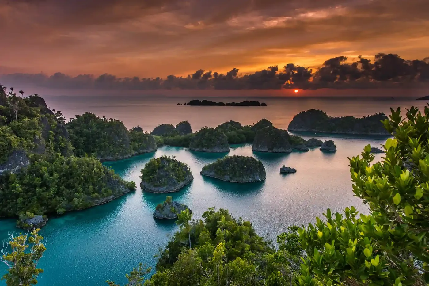 Sunset over the karst islands and still lagoons of Piaynemo, the sky burning orange above the ridgeline